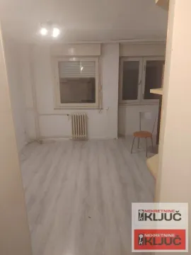 Prazna soba sa laminatom, radijatorom i stolicom. - image 2