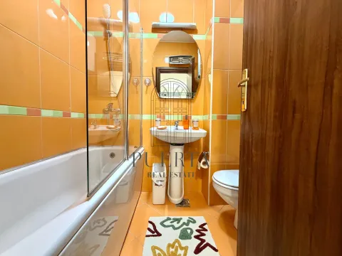Manje kupatilo obloženo narandžastim pločicama sa kadom i umivaonikom. - image 16