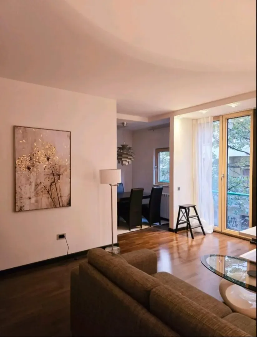 Living room with a sofa, dining area in the background, and access to the terrace.