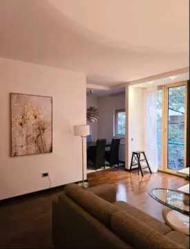 Living room with a sofa, dining area in the background, and access to the terrace. - image 2