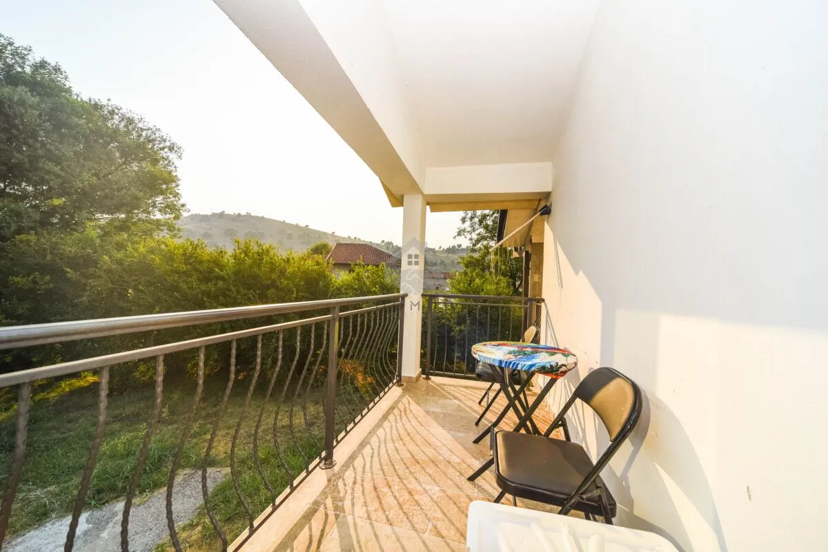 Natkriveni balkon sa metalnom ogradom i pogledom na prirodu i brda.