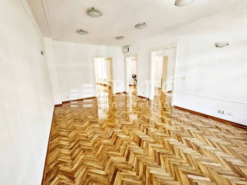Empty living room with parquet flooring and white walls.
