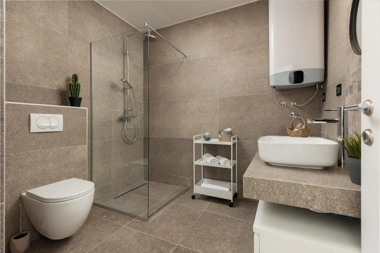 Modern bathroom equipped with a walk-in shower, washbasin, and toilet.