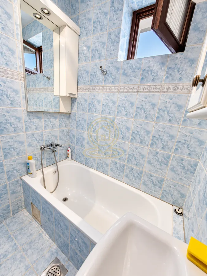 Bathroom with blue tiles and a bathtub.
