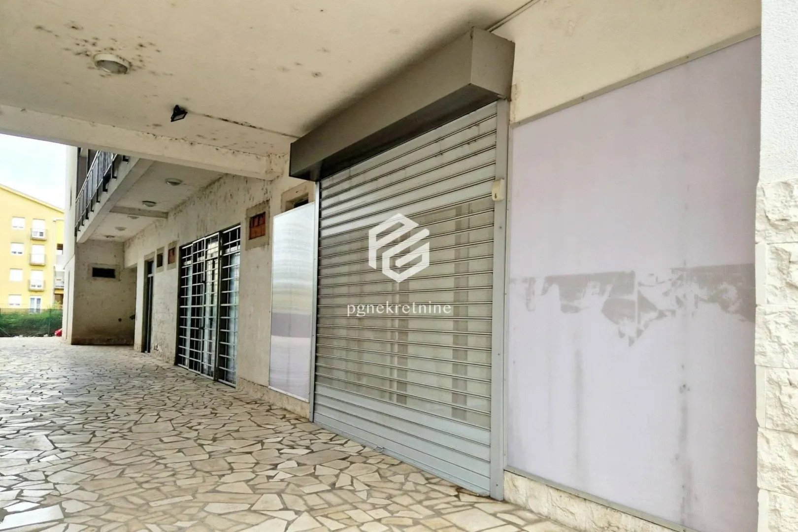 Exterior view of a commercial space with roller shutter on the ground floor of the building.