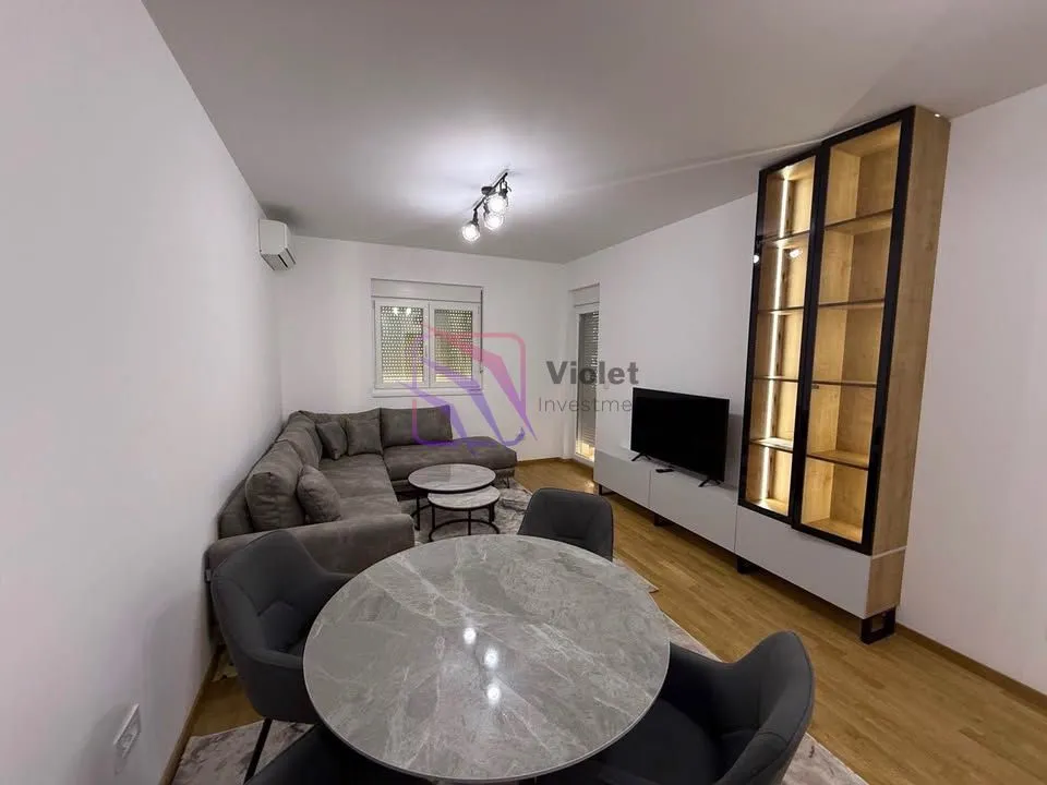 Living room with a corner sofa, dining table, and TV unit.