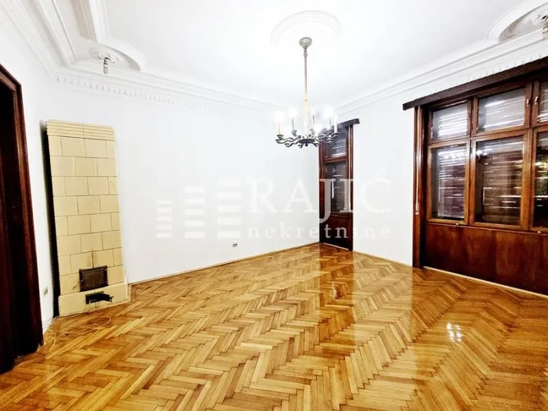 Empty room with parquet flooring and a traditional wood-burning stove.