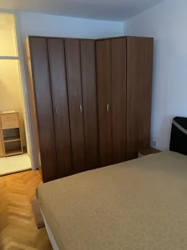 Spavaća soba sa velikim drvenim ormarom i krevetom. - image 14