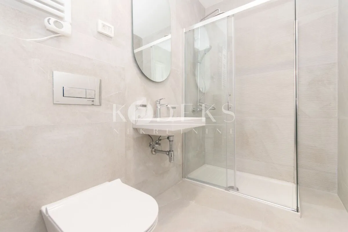 Moderne kupatilo sa tuš kabinom, umivaonikom i ugradnom wc šoljom.