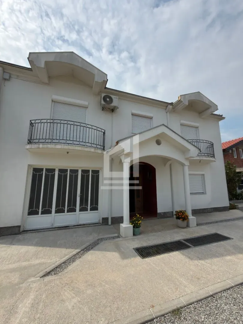 Front view of a white two-story house with a paved yard.