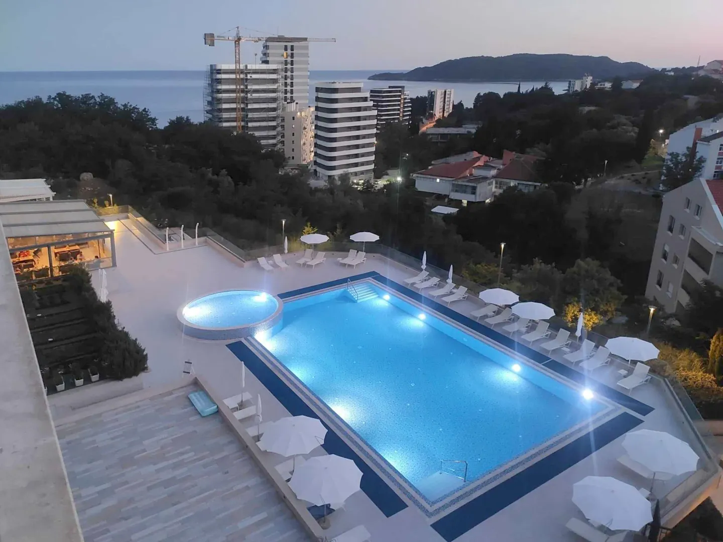Aerial view of an outdoor swimming pool with sun loungers and umbrellas.