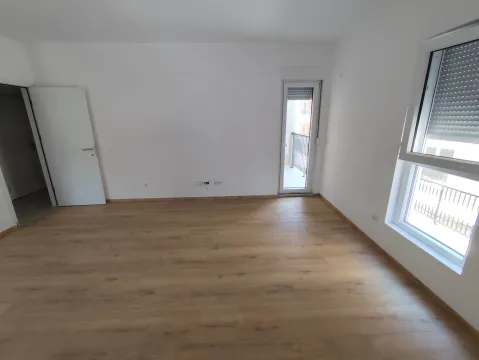 Empty room with white walls, wooden flooring, a window, and a balcony door. - image 3