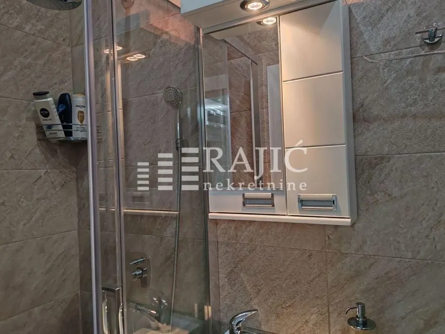 Modernly equipped bathroom with a shower cabin and a mirror.