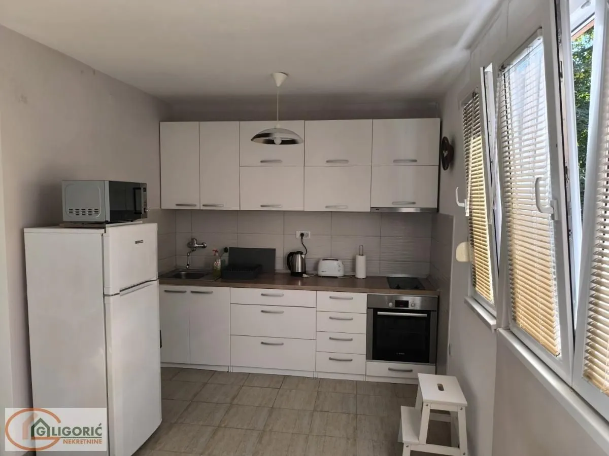 Small white kitchen with all built-in appliances and a refrigerator.