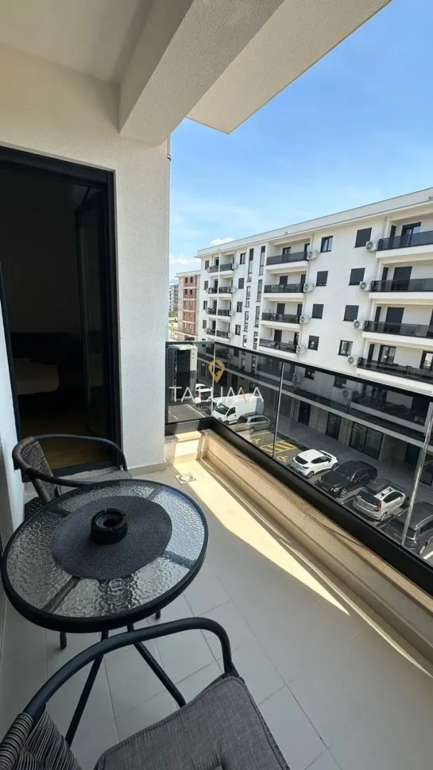 Furnished balcony with a table and chairs and a view of the parking lot and buildings.