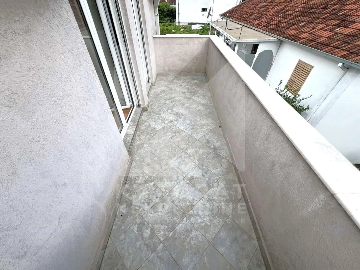 Prazan popločani balkon sa ogradom.