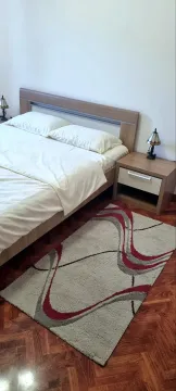 Namještena spavaća soba sa bračnim krevetom, noćnim stočićem i tepihom. - image 5