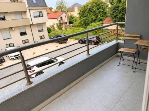 Small tiled balcony with seating furniture and a view of the parking lot and buildings. - image 4