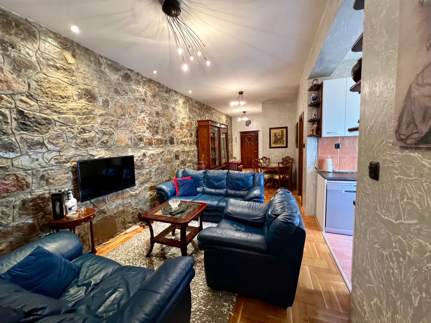 Spacious living room with leather sofas and a stone-clad wall.