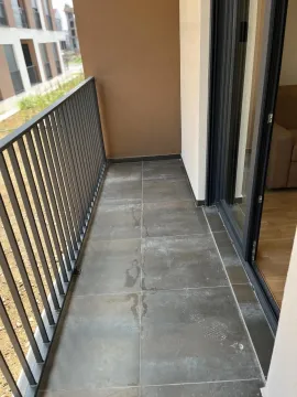 Uski balkon sa sivim pločicama i metalnom ogradom. - image 7