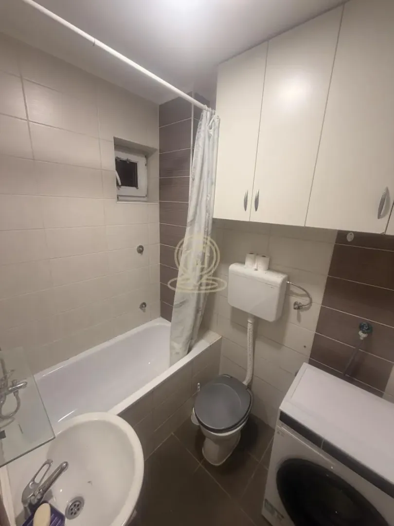Small bathroom with a bathtub, toilet, washbasin, and built-in cabinet.