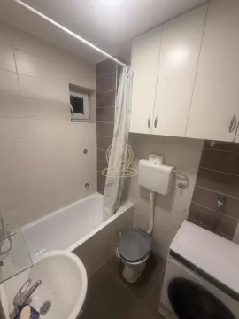 Small bathroom with a bathtub, toilet, washbasin, and built-in cabinet. - image 6