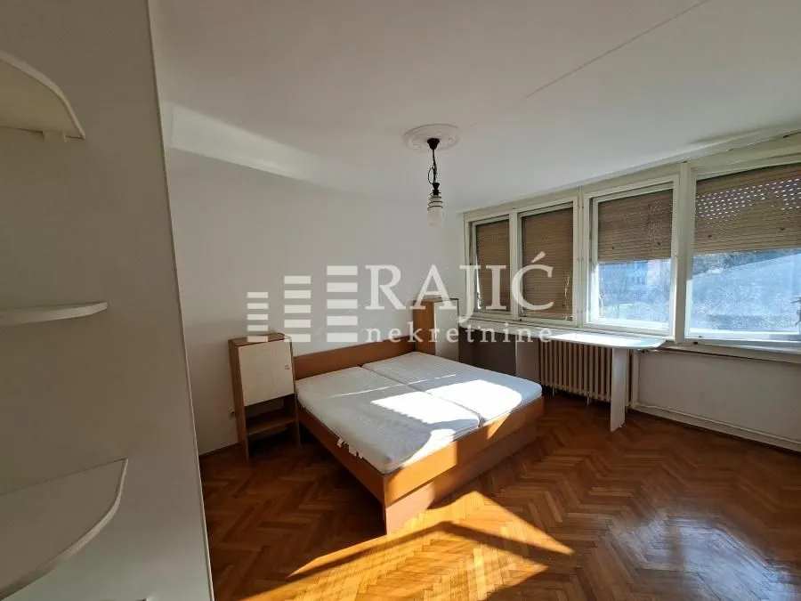 Furnished bedroom with a double bed and parquet flooring.
