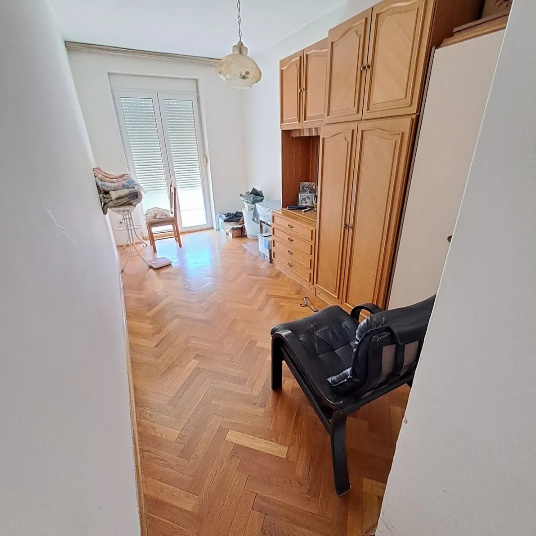 Dnevna soba sa parketom, drvenim garderoberom i izlazom na terasu.