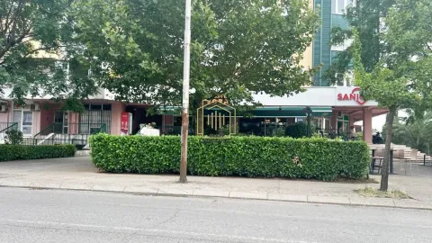 View of the building exterior with a trimmed hedge and trees in front. - image 2