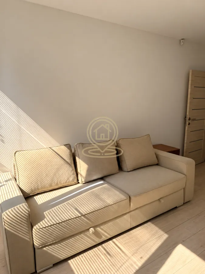 Beige sofa in a bright room with a wooden floor and sunlight.