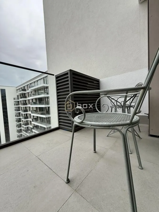 Small furnished balcony with chairs and a glass railing.
