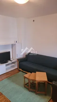 Dnevna soba sa garniturom za sedenje, televizorom i malim stočićem. - image 4