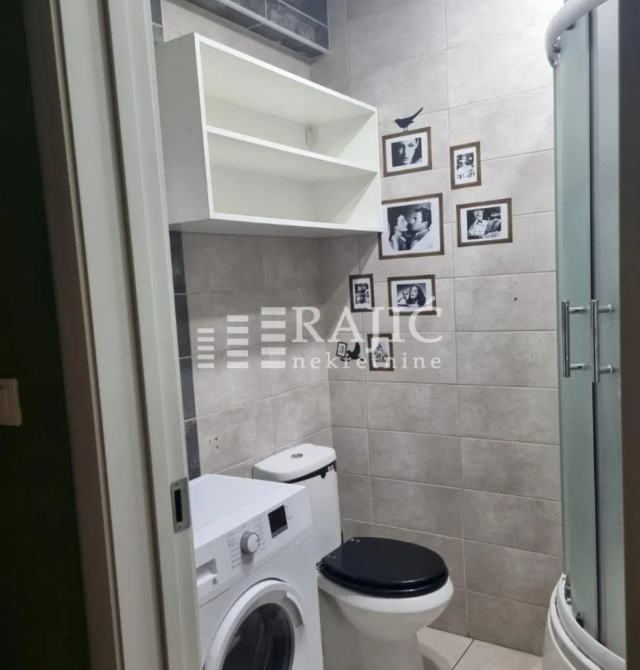 Smaller bathroom with a shower cabin, toilet, and washing machine.