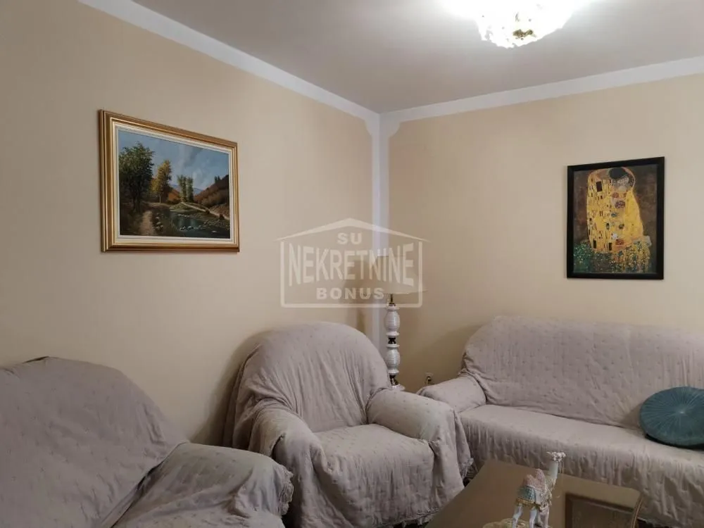 Dnevna soba sa garniturom za sedenje i slikama na zidu.