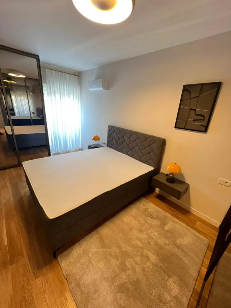 Modern bedroom with a double bed, bedside tables, and a large mirrored wardrobe.