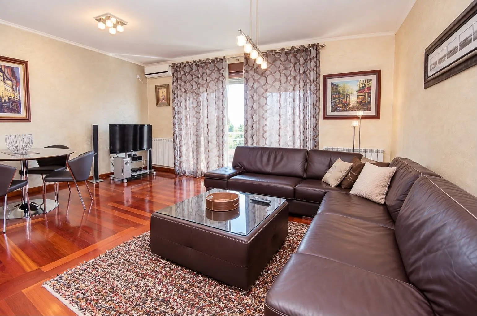 Spacious living room with a sofa set, dining table, and hardwood flooring.