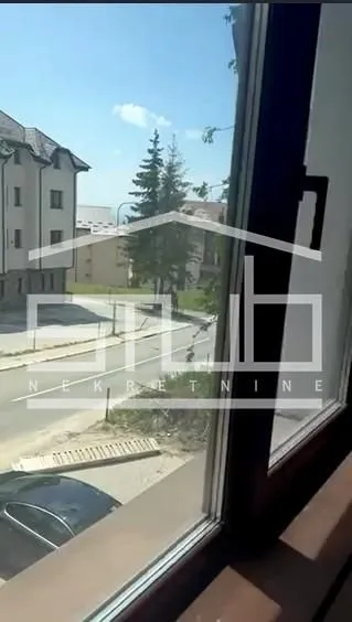 Pogled kroz prozor na ulicu i okolne zgrade.