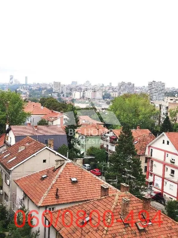 Pogled sa prozora na gradski pejzaž i krovove zgrada.