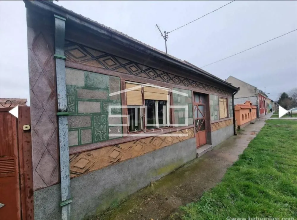 Pogled na spoljašnjost kuće sa fasadom i dvorištem.