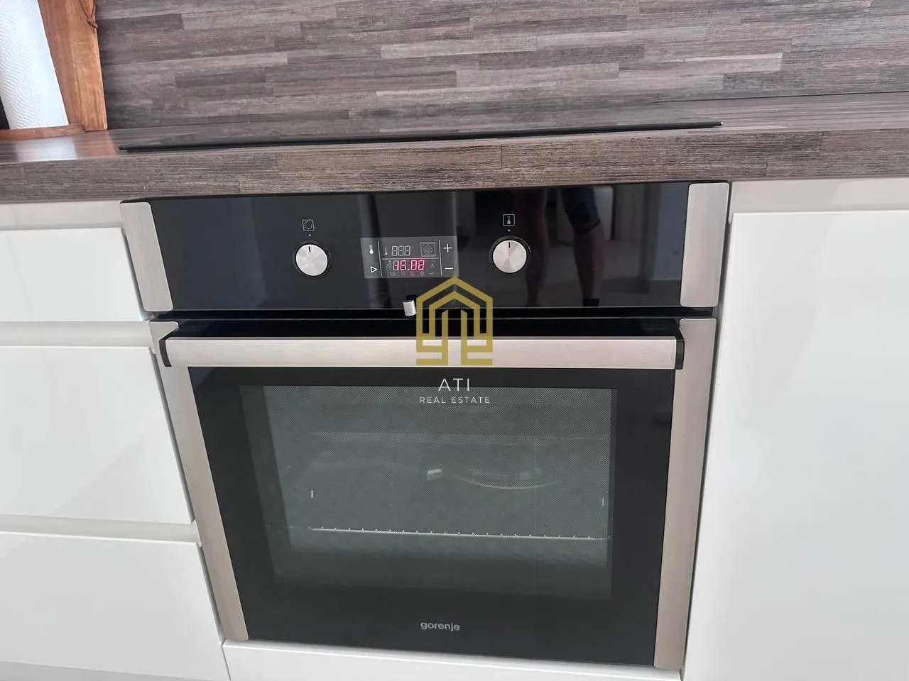 Modern built-in oven in a white kitchen with a wooden countertop.