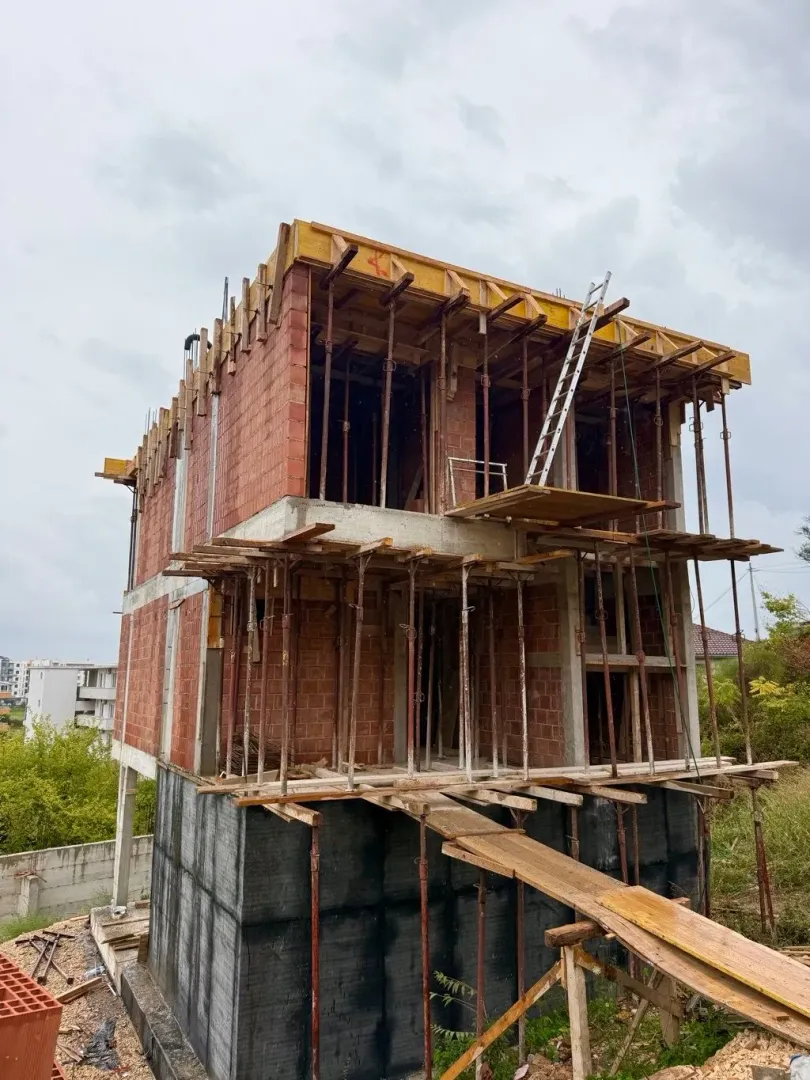 View of a house under construction with scaffolding and formwork.