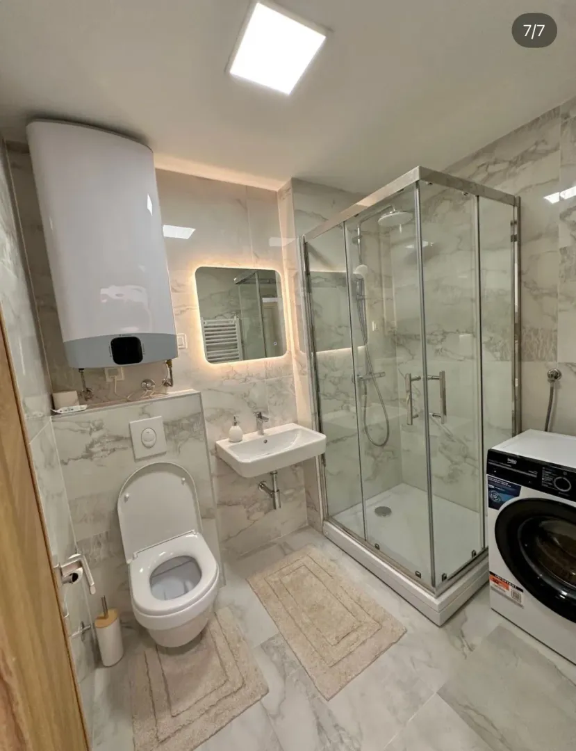 Moderne kupatilo sa tuš kabinom, umivaonikom, WC šoljom i bojlerom.