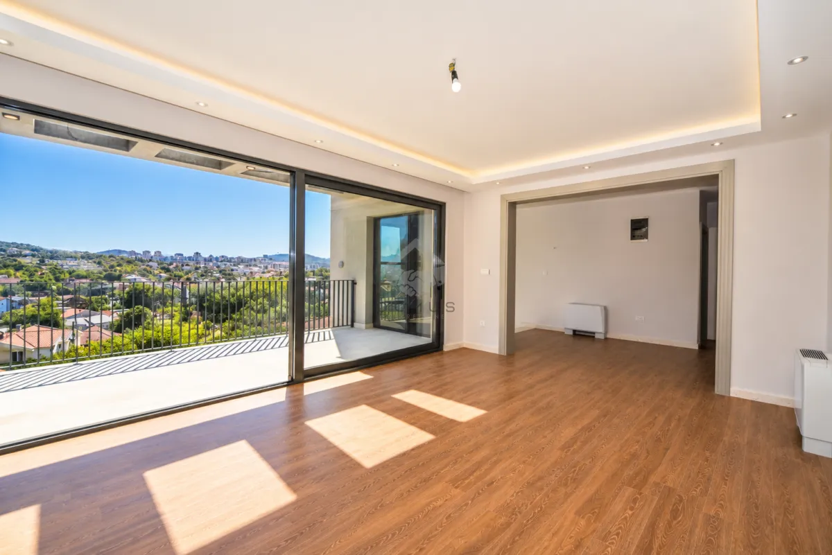 Empty living room with a large glass door leading to the terrace.