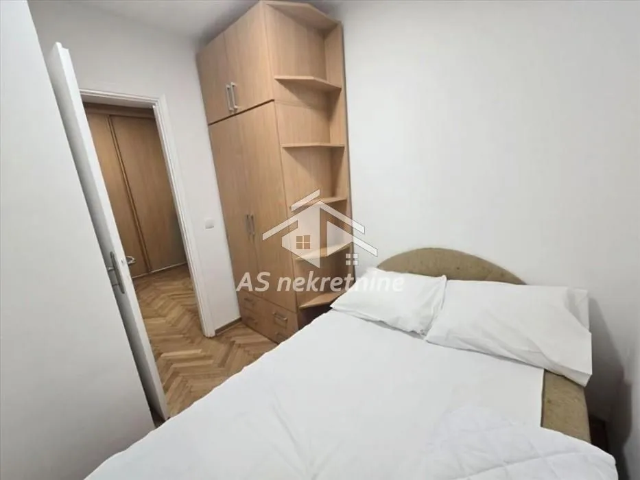 Smaller bedroom with a bed and a wooden wardrobe.