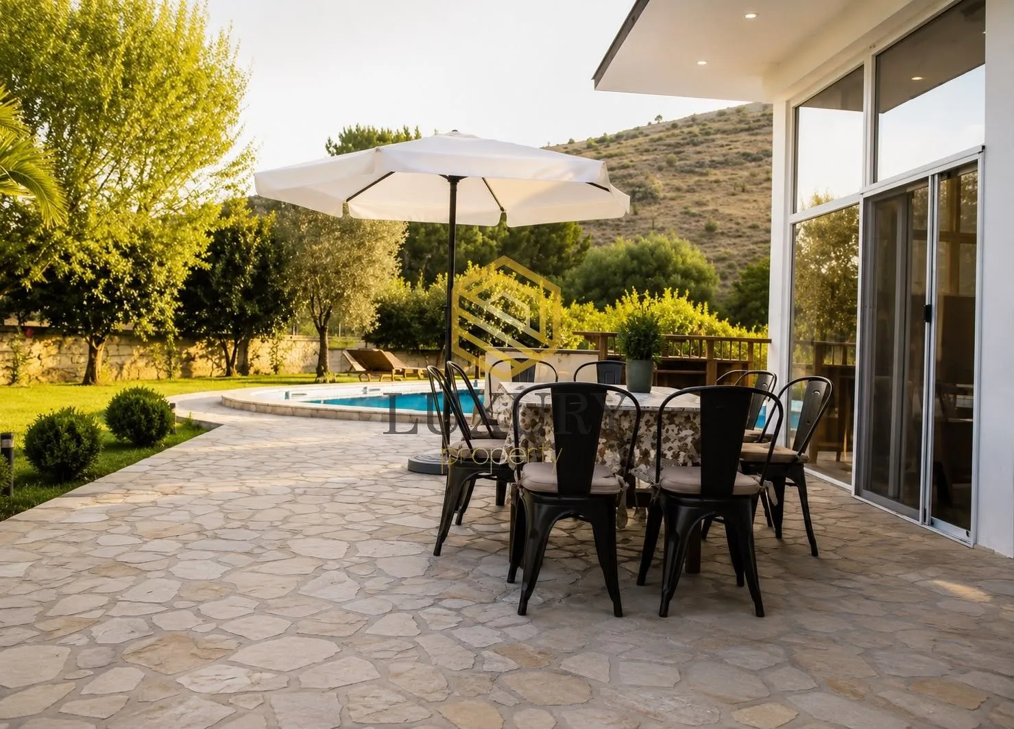 Terrace with a dining table overlooking the pool and yard.