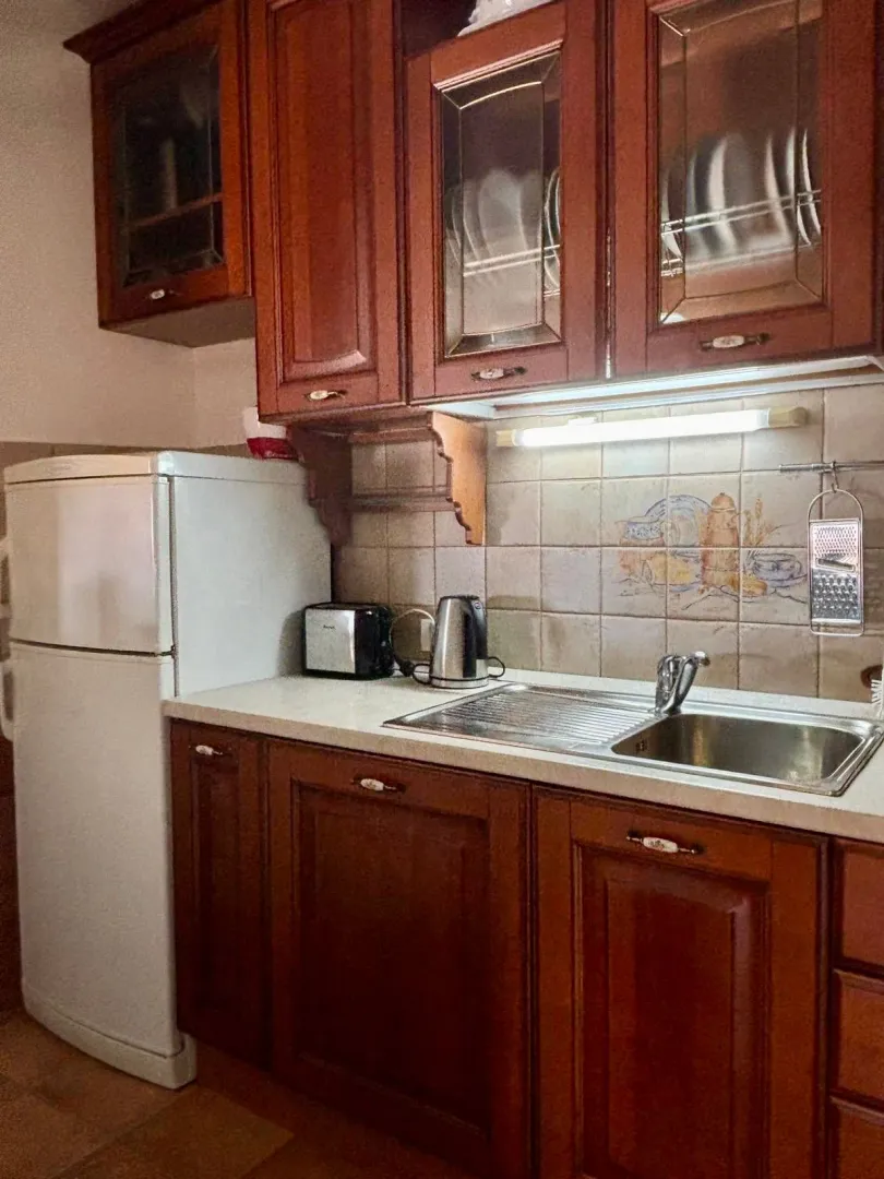 Kitchen with wooden cabinets, a sink, and a white refrigerator.