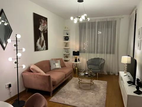 Uređena dnevna soba sa roze trosjedom, foteljom i modernom rasvjetom. - image 11