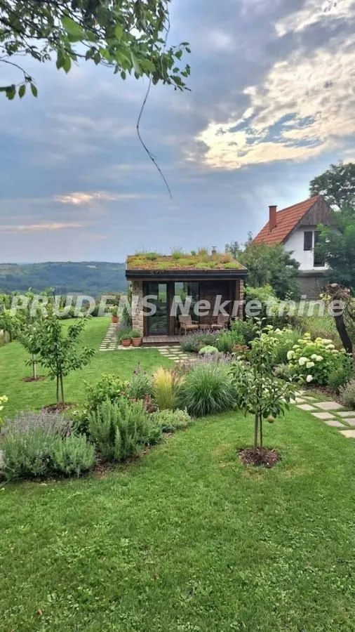 Lepo uređeno dvorište sa travnjakom, zelenilom i pomoćnim objektom.