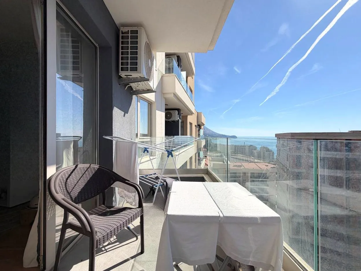 Namješten balkon sa stolom, stolicama i pogledom na more.