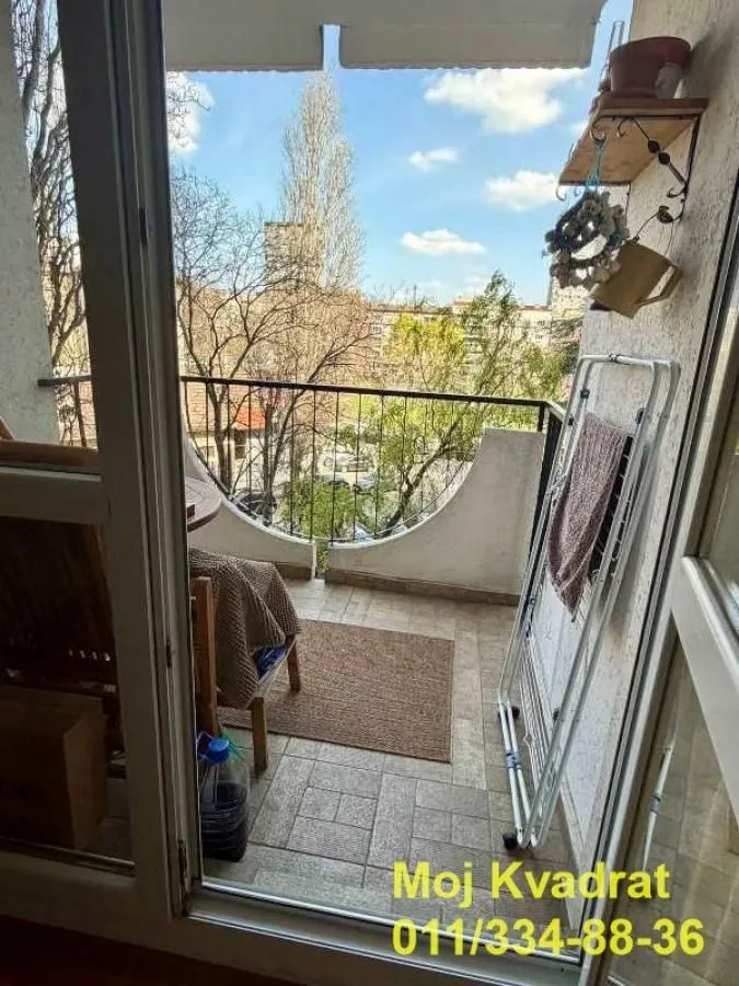 Manji namešteni balkon sa pogledom na ulicu i drveće.